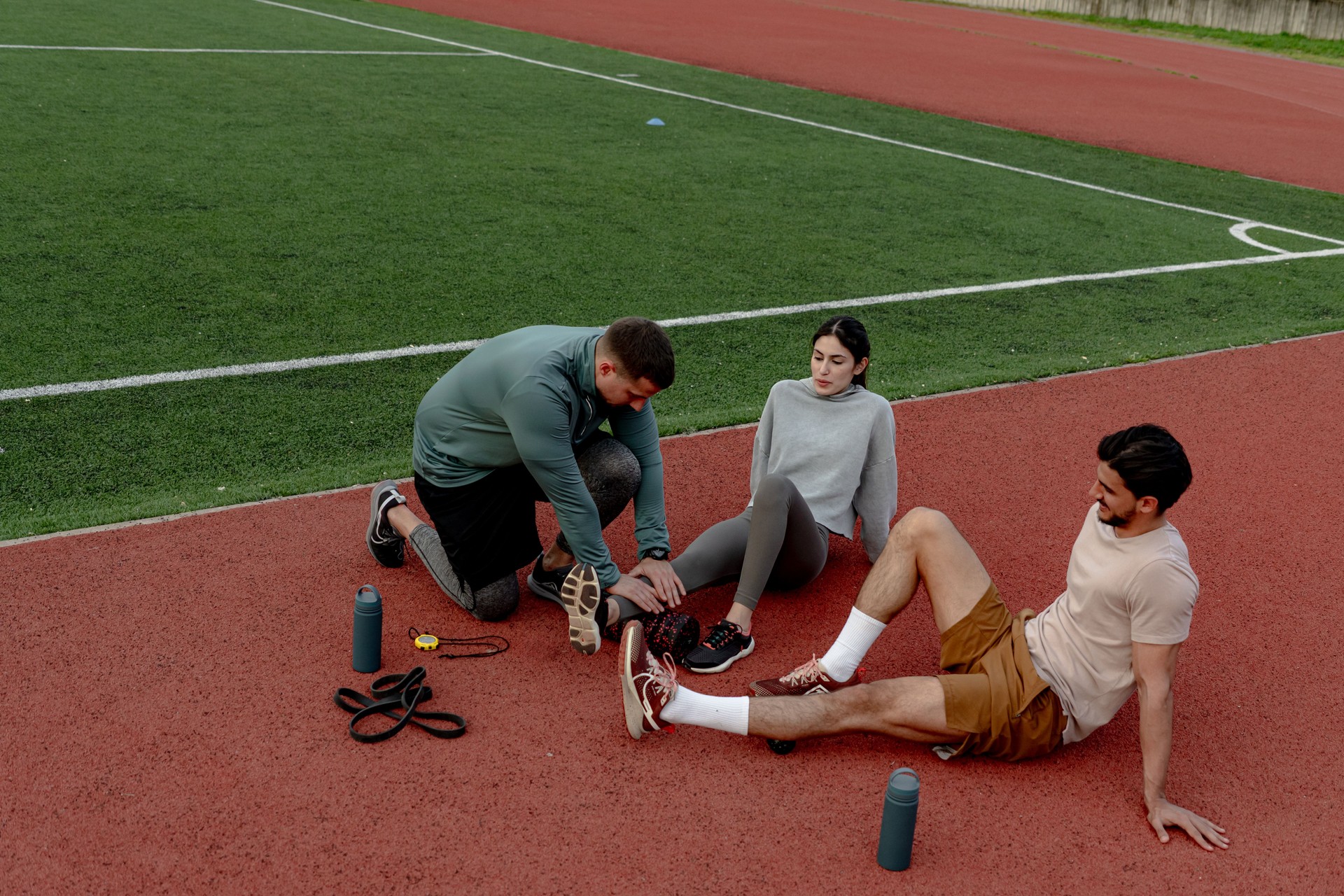 Trainer assisting injured athlete on running track